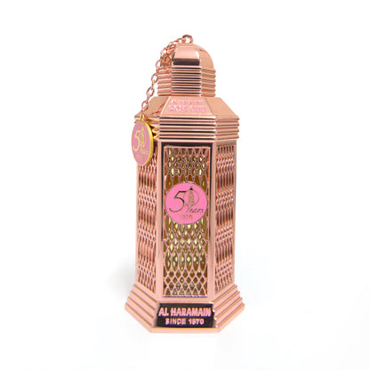 A pink colored bottle of Rose Oud Eau de Parfum by Al Haramain with a decorative cap and label, displayed against a white background.