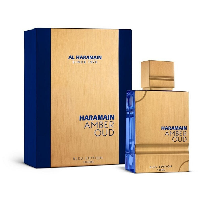 A product image featuring a perfume bottle and box for Al Haramain's Amber Oud Blue Eau de Parfum. The bottle is blue with gold accents, and the box is gold with blue accents.