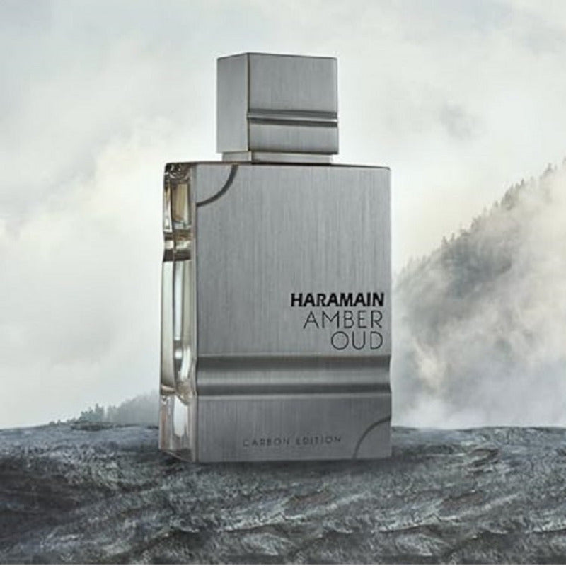 Haramain Amber Oud perfume bottle on a rocky surface with a mountainous background