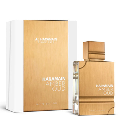 A product image featuring Al Haramain Amber Oud White Edition Eau de Parfum in a glass bottle with a gold-colored label and cap, alongside its white box packaging with the product name and brand logo.