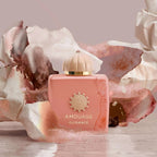 Pink Amouage Guidance perfume bottle with gold cap on a decorative background