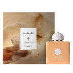 A bottle of Amouage Love Delight eau de parfum for women, accompanied by its packaging box. The bottle is cream-colored with a white cap, and the box features a floral design.