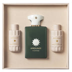 Amouage Purpose bath and shower gift set in a beige presentation box, featuring a dark green rectangular bottle in the center with a white cap, flanked by two cream-colored bottles labeled bath & shower oil and bath & shower gel.