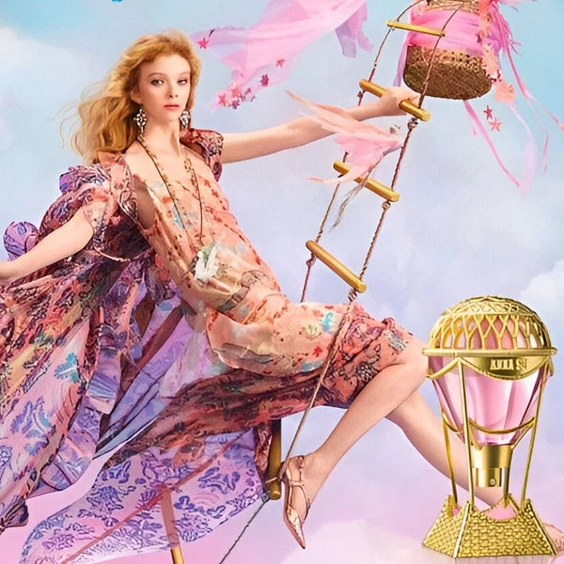 Woman in a floral dress sitting on a swing with pink ribbons against a light blue sky.