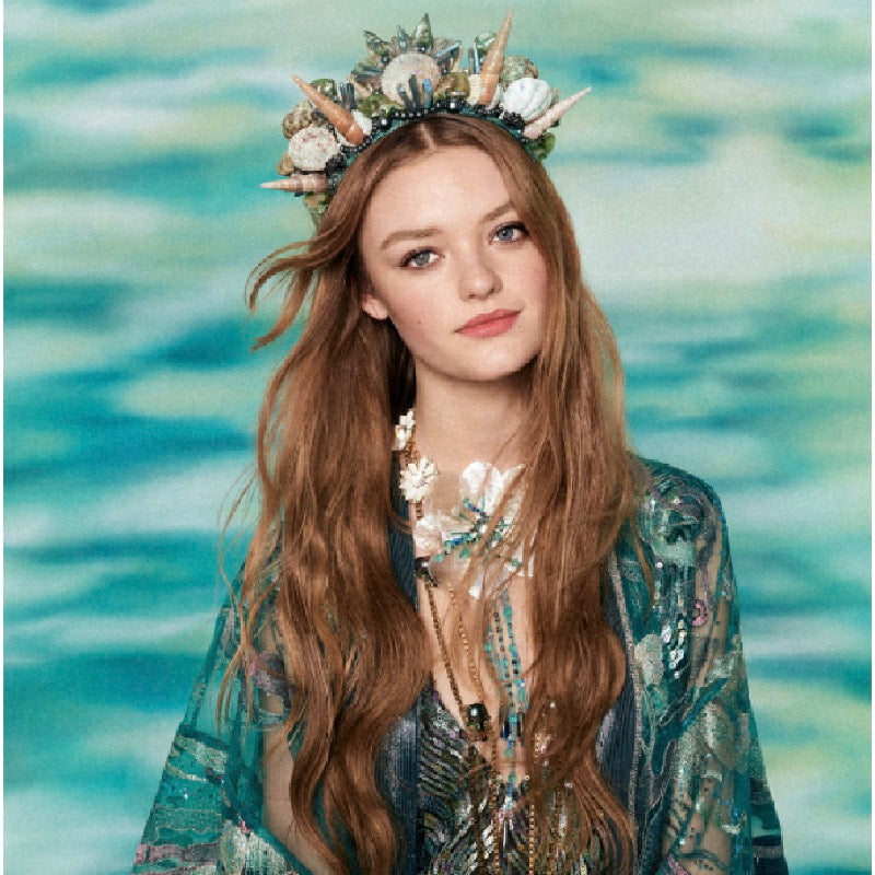 Woman with a decorative headpiece and long hair against a water background