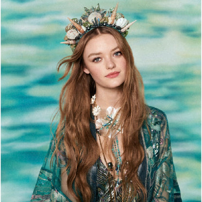 Woman with a decorative headpiece and long hair against a water background