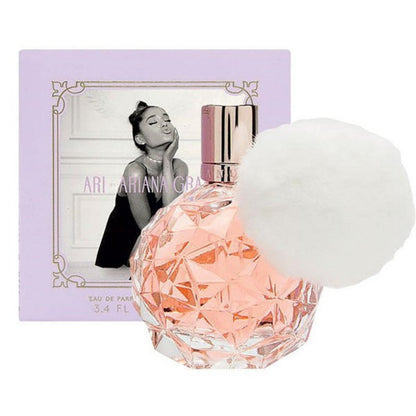 A bottle of ARI Eau de Parfum by Ariana Grande with the product packaging in the background, featuring a black and white photo of Ariana Grande.