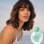 Woman with a light blue background and a Giorgio Armani perfume bottle.