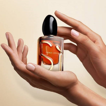 Hand holding a Giorgio Armani perfume bottle against a beige background