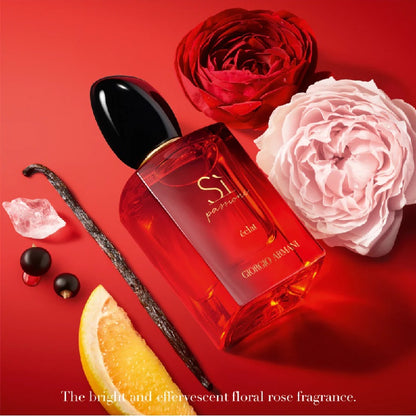 Perfume bottle with red and pink roses, vanilla bean, and orange slice on a red background