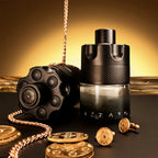 Black perfume bottle with gold coins and chain on a reflective surface