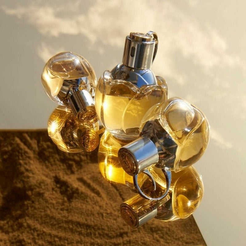 Gold perfume bottle with silver cap on a reflective surface