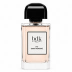 A bottle of Bdk Parfums Paris Saint-Honoré fragrance, featuring a clear glass bottle with a pale peach-pink liquid, a white label with black text, and a glossy black cap, set against a plain white background.