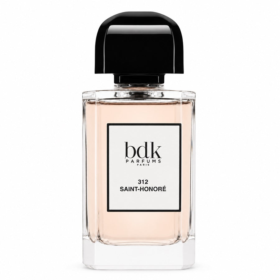 A bottle of Bdk Parfums Paris Saint-Honoré fragrance, featuring a clear glass bottle with a pale peach-pink liquid, a white label with black text, and a glossy black cap, set against a plain white background.