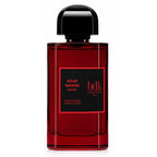 A bottle of Bdk Parfums Rouge Smoking Extract extrait de parfum, featuring a deep red translucent glass bottle with a black cap and a black label with red text.