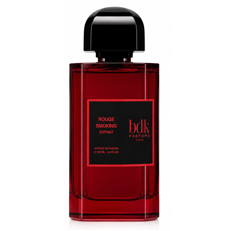 A bottle of Bdk Parfums Rouge Smoking Extract extrait de parfum, featuring a deep red translucent glass bottle with a black cap and a black label with red text.