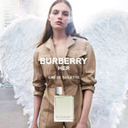 Woman with angel wings holding a Burberry Her perfume bottle.