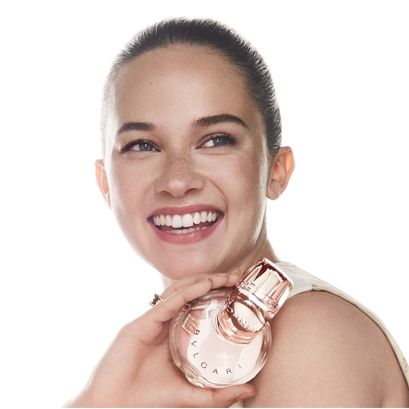 Woman holding a Bulgari perfume bottle against a white background