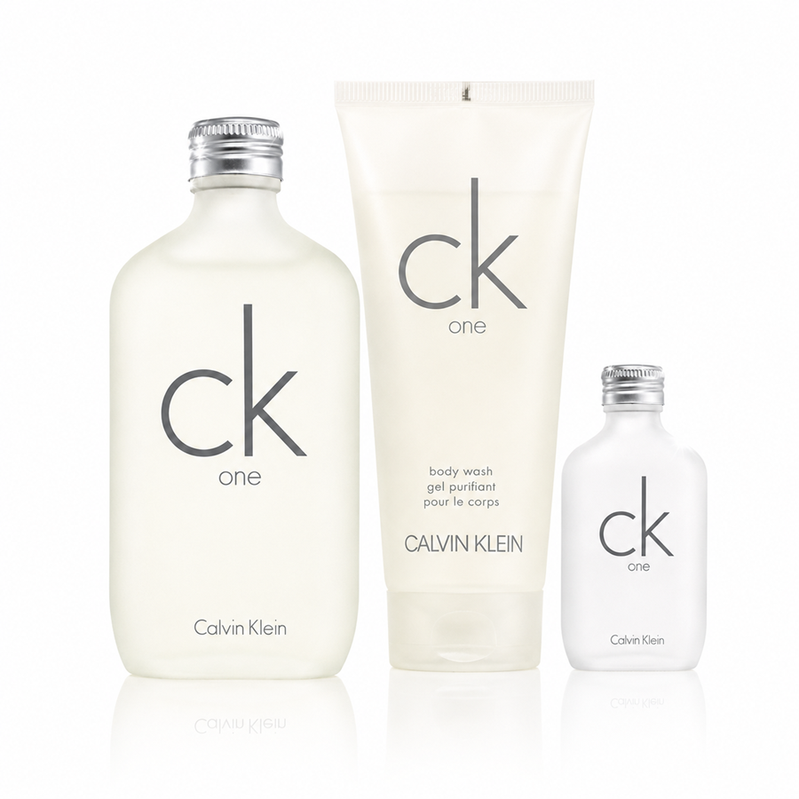 Calvin Klein CK One body wash set featuring a large frosted bottle, a tall translucent tube, and a smaller clear bottle, all with silver caps on a white background.