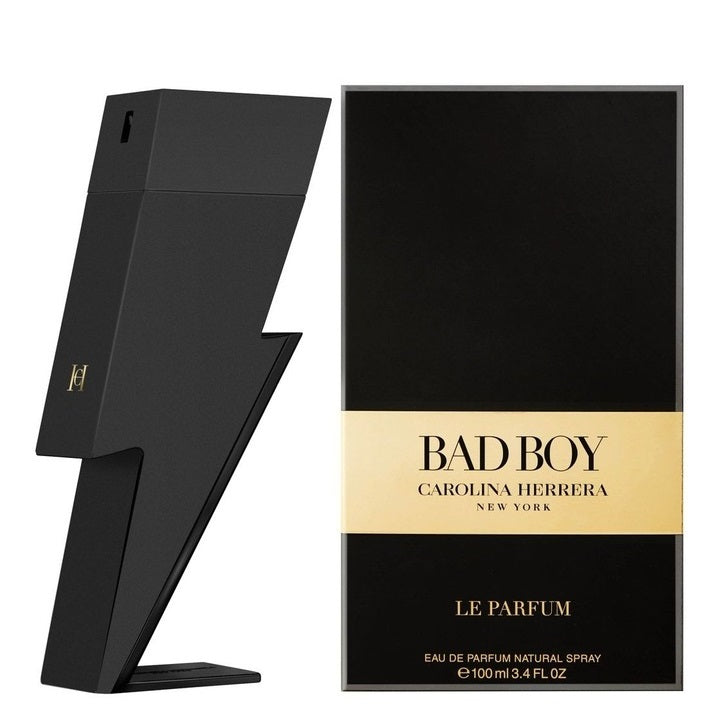 The image shows the product packaging and bottle of Bad Boy Le Parfum by Carolina Herrera. The packaging is predominantly black with gold accents, and the bottle is designed in a unique, angular shape.