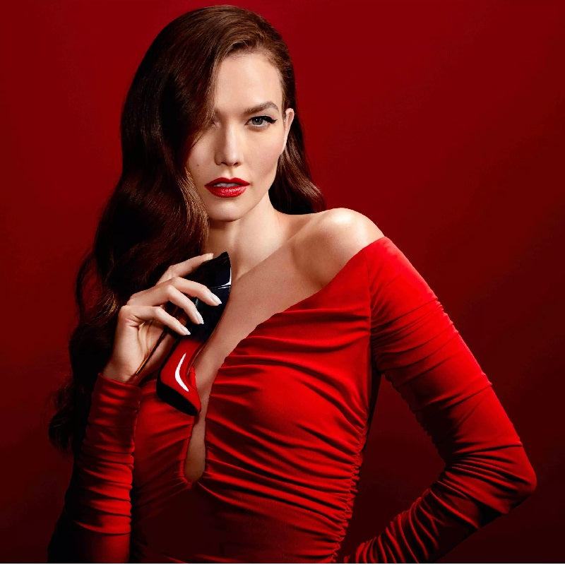 Woman in a red dress holding a phone against a red background