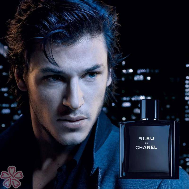 Man with a bottle of Bleu de Chanel perfume against a dark background