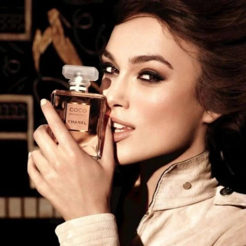 Woman holding a Chanel Coco perfume bottle with a blurred background