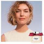 Woman with a Chélo perfume bottle on a clear blue sky background