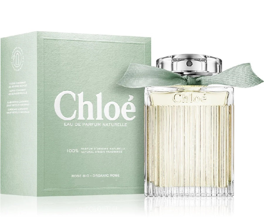 A bottle of Chloe Naturelle Eau de Parfum with its packaging box, both featuring a light green color. The perfume bottle is transparent, showcasing the light-colored liquid inside.