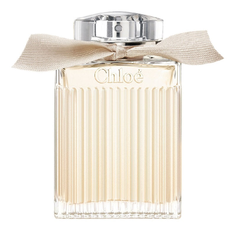A bottle of Chloe Signature Eau de Parfum with a clear, golden hue and a decorative bow on the cap.
