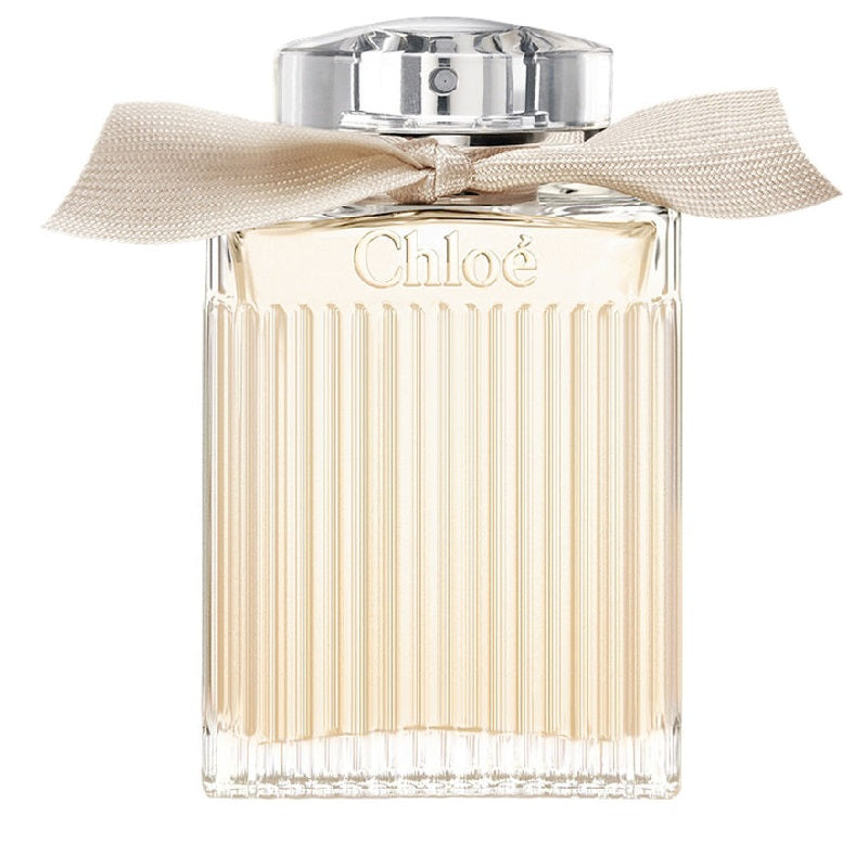 A bottle of Chloe Signature Eau de Parfum with a clear, ribbed design and a beige ribbon at the neck.