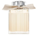 A bottle of Chloe Signature Eau de Parfum with a clear, ribbed design and a beige ribbon at the neck.