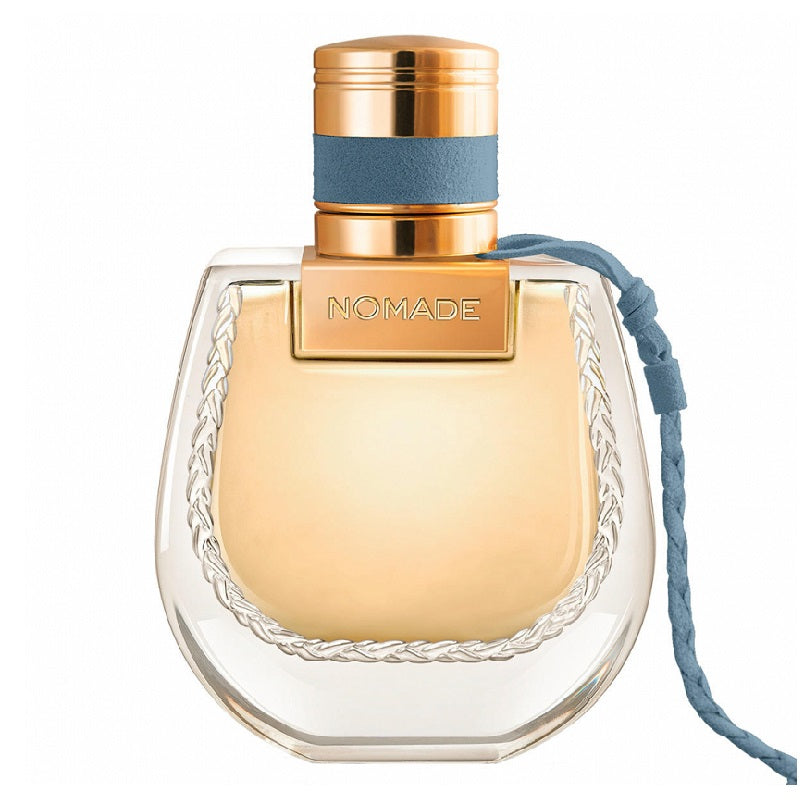 Perfume bottle labeled 'Nomade' with a gold cap and clear body on a white background