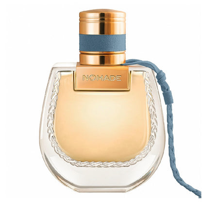 Perfume bottle labeled 'Nomade' with a gold cap and clear body on a white background