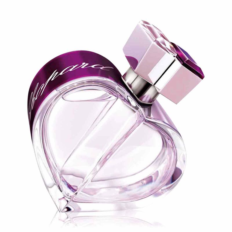Chanel No. 5 Eau de Parfum bottle with a heart-shaped clear glass body, a metallic purple collar with white script, and a faceted pink cap on a white background.