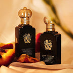 Two Clive Christian perfume bottles on a soft background with fruit.