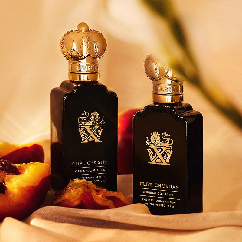 Two Clive Christian perfume bottles on a soft background with fruit.