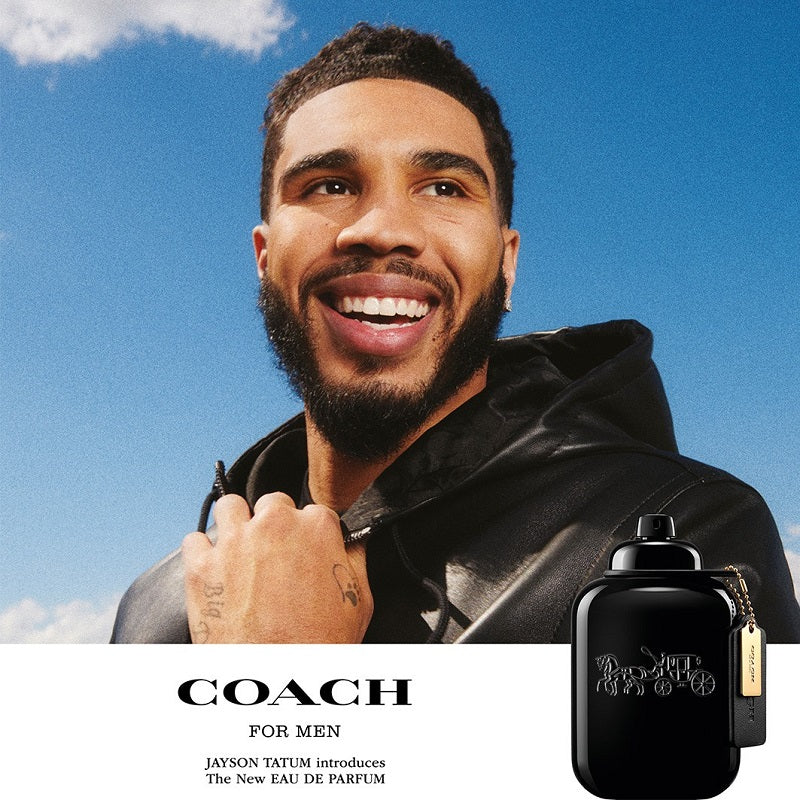 Man holding a Coach for Men perfume bottle against a blue sky
