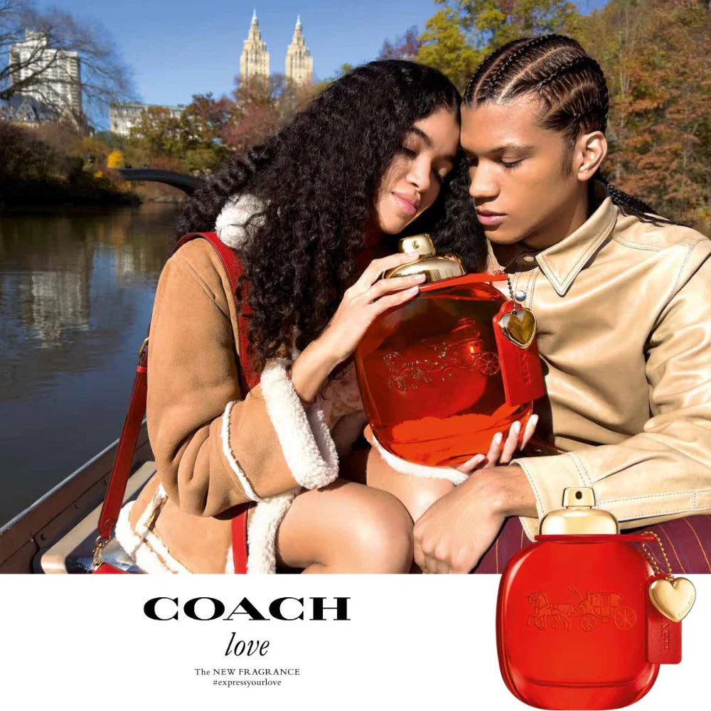 Two people holding a large red Coach perfume bottle with Central Park in the background.