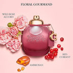 Pink perfume bottle with floral and fruit elements on a pink background