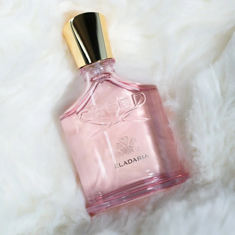 Pink perfume bottle with gold cap on a white fur background