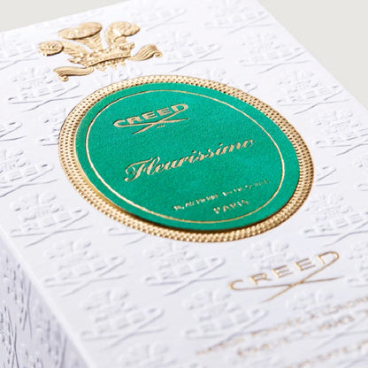 Close-up of a Creed perfume box with gold and green design on a white background