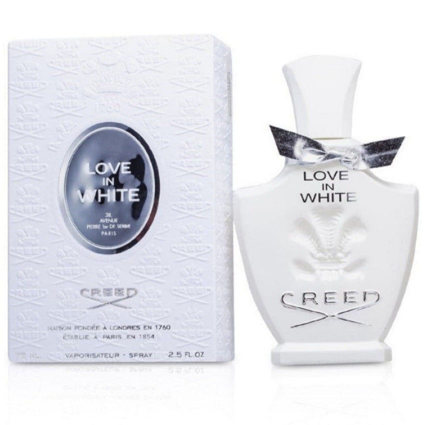 A bottle of 'Love In White' eau de parfum by Creed with the cap off, next to its packaging box. The bottle and box are both white with gold and black detailing.