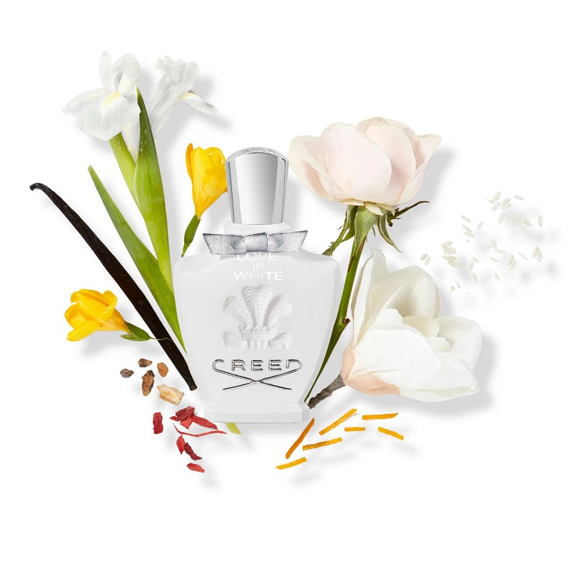Creed perfume bottle surrounded by flowers and vanilla beans on a white background