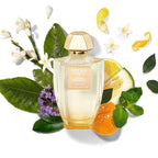 Creed perfume bottle surrounded by citrus fruits and flowers on a white background