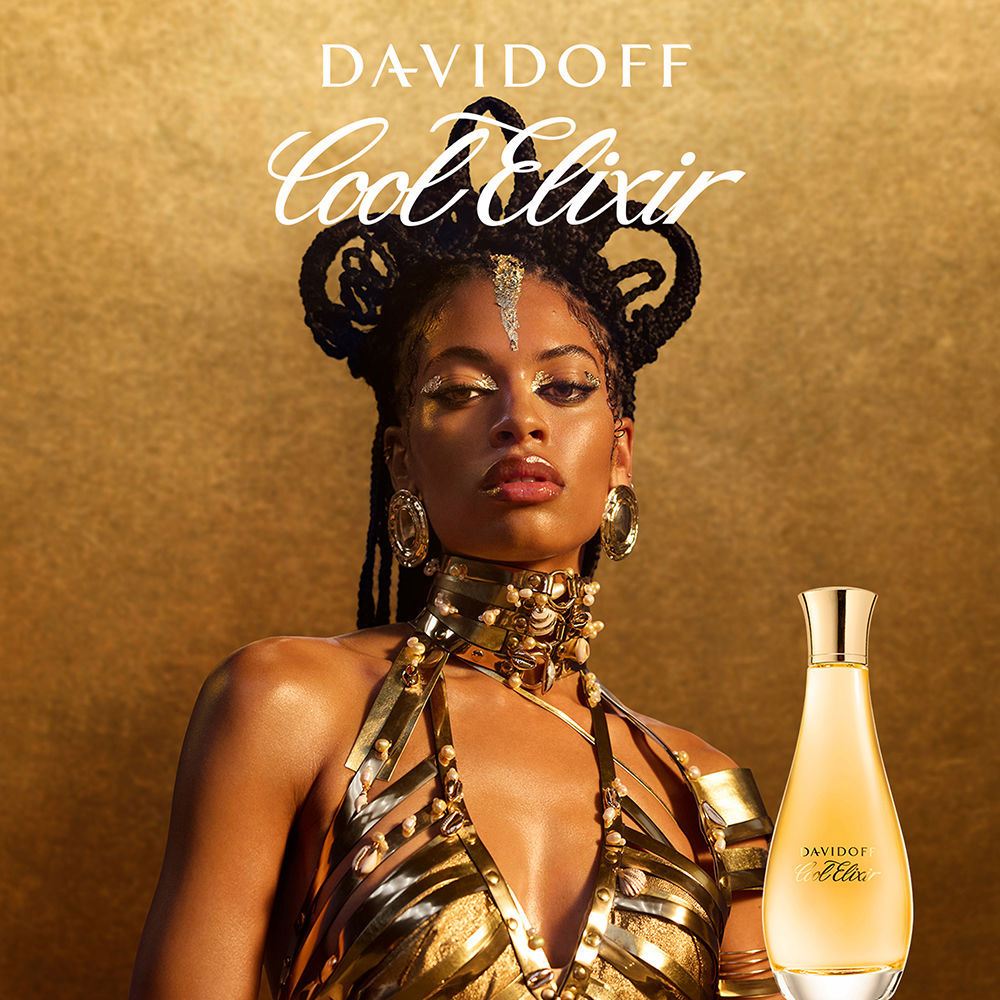 Model wearing gold and black attire with Davidoff Cool Elixir perfume bottle on a gold background
