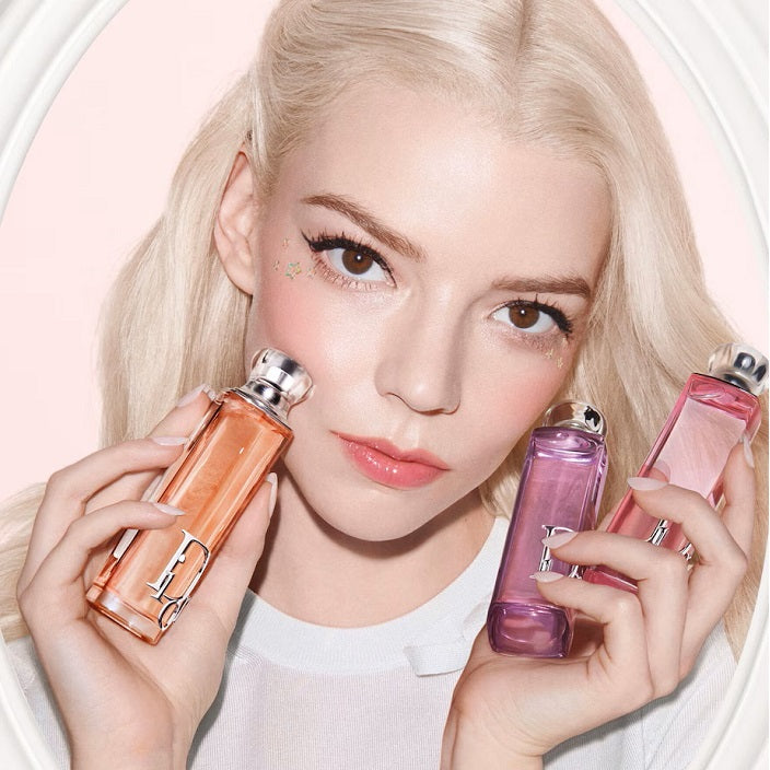 Woman holding three perfume bottles against a light background