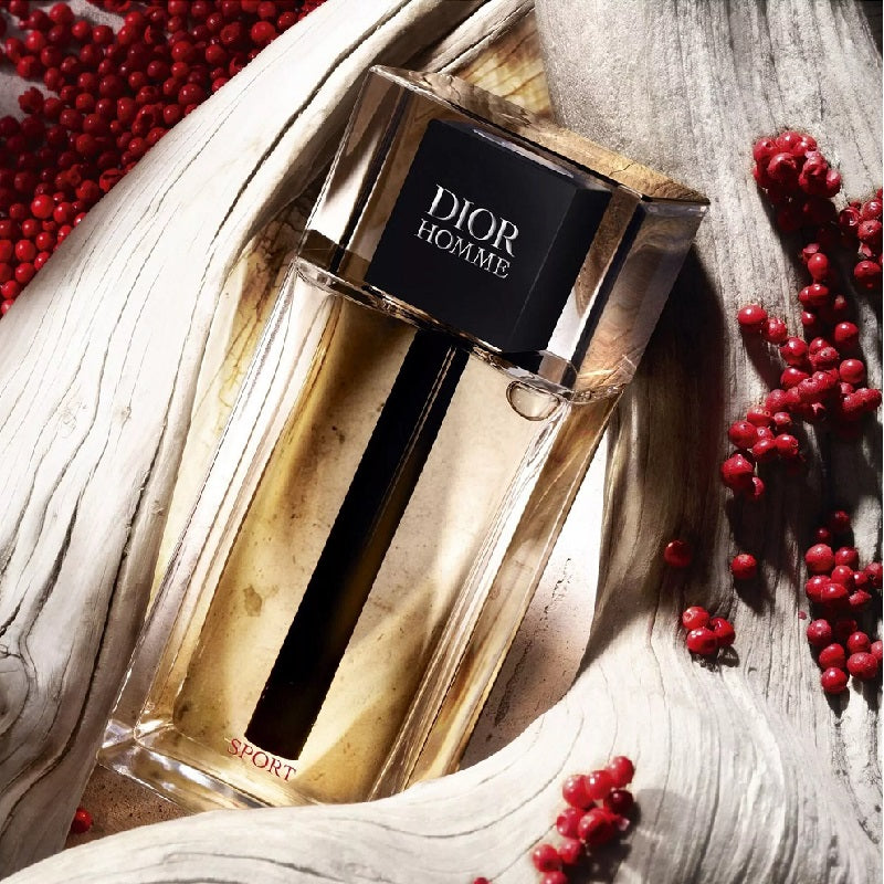 Dior Homme perfume bottle with red berries on a textured surface
