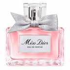 Miss Dior Eau de Parfum bottle with pink liquid, a silver glitter bow, and a clear cap on a white background.