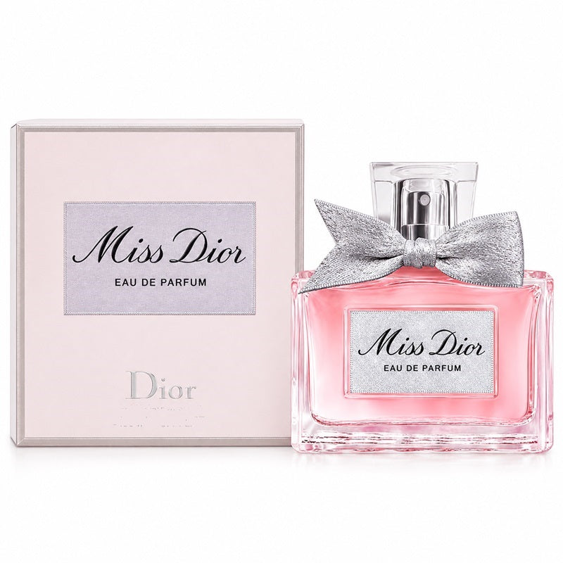 Dior Miss Dior Eau de Parfum bottle with a silver bow next to its light pink packaging box on a white background.